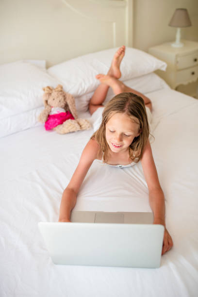 istock Cute little girl doing homework on laptop 1221059727