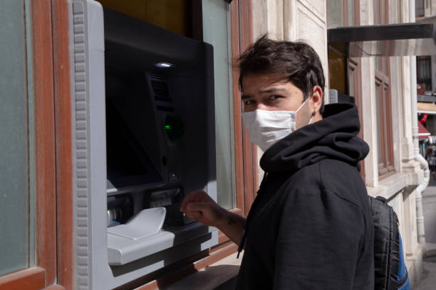 istock The young man performs his transactions from the bank atm using his protective mask. 1221059786