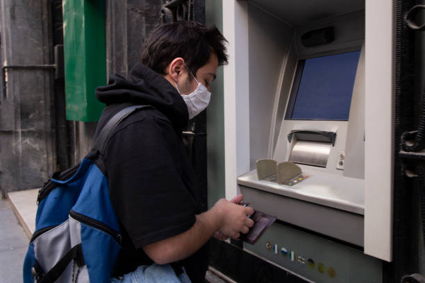 istock The young man performs his transactions from the bank atm using his protective mask. 1221059787