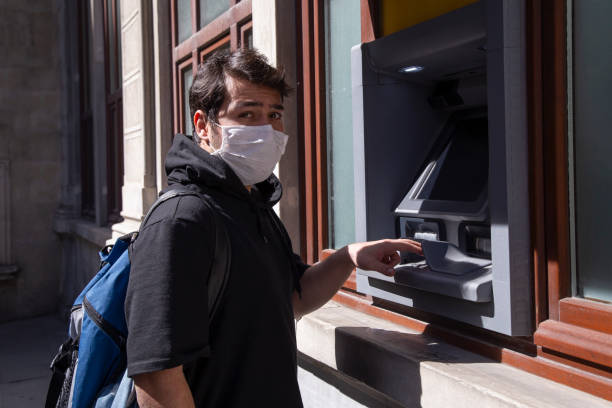 istock The young man performs his transactions from the bank atm using his protective mask. 1221059791