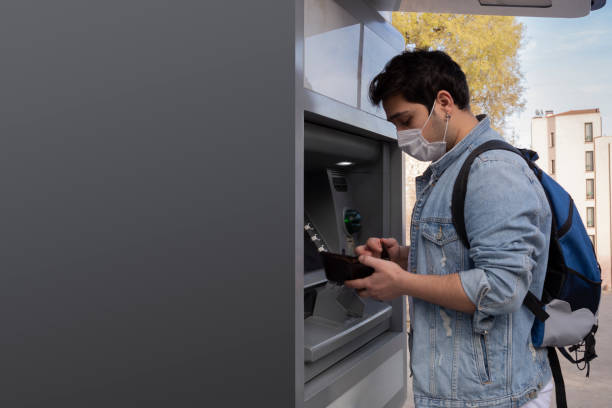 istock The young man performs his transactions from the bank atm using his protective mask. 1221059825