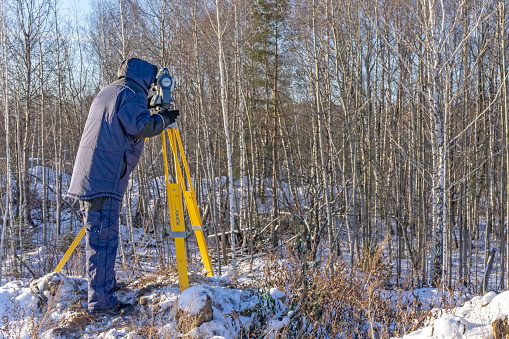 Surveyor in the winter forest conducts cadastral work