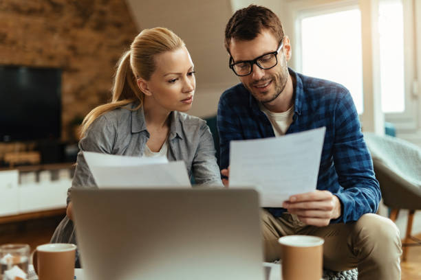 istock Smiling couple going through paperwork while working together at home. 1221060124
