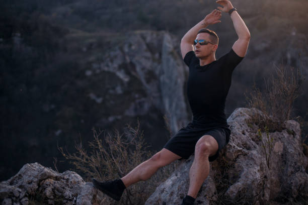 istock Young man sitting on the rock on the mountain 1221060408