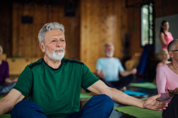 istock Senior man meditating and relaxing on a group yoga class 1221063923