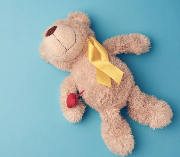 istock teddy bear holds in his paw a yellow ribbon folded in a loop on 1221064831