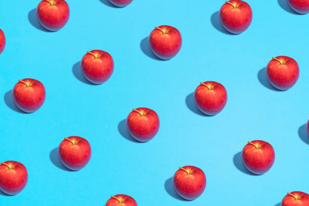 istock Minimal flat lay food texture. Summer abstract trendy fresh concept. red Apple pattern on bright light blue background, copy space 1221066155