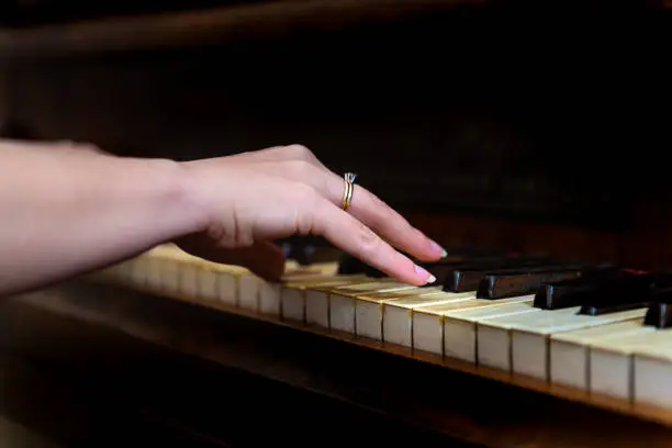 Old forte piano with female woman hand and diamond ring finger pianist playing closeup for concert with black background