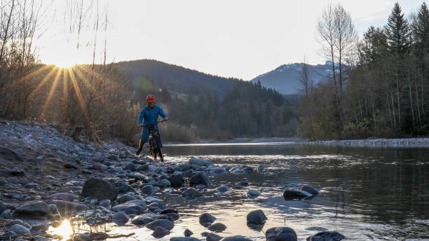 mountain biker relaxa ao lado do rio ao nascer do sol - stone wellbeing zen like blue - fotografias e filmes do acervo