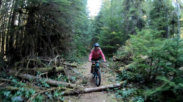istock Female mountain biker rides along forested path 1221079935