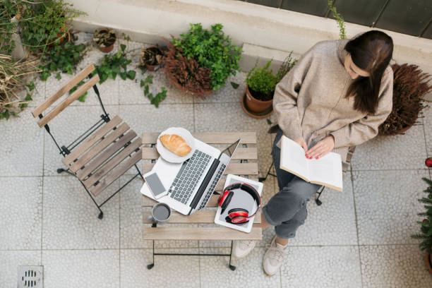 istock Young woman reading a book on a balcony 1221081259