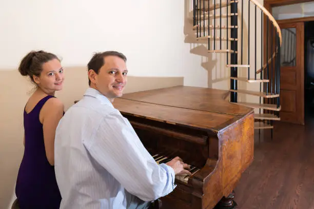 Old piano with young woman man romantic couple sitting in room pianist playing in formal dress in room for concert together looking at camera