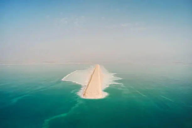 Photo of Road on Dead Sea surface. The southern part of the Dead Sea, is divided into pools from which extract minerals. shore is covered with white salt crystals washed by the blue waters of the dead sea