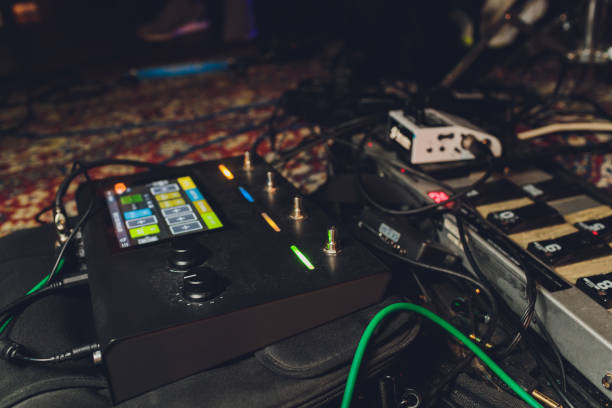 istock Electric guitar and guitar audio processing effects on a studio floor. Electric guitar and stomp box type effectors and cables on studio floor. Intentionally shot with low key tone. 1221082343