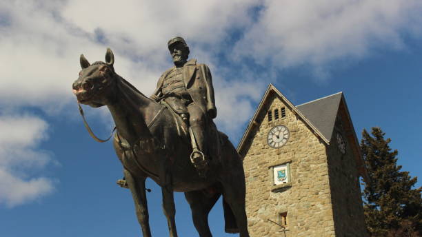 denkmal von julio argentino roca reiten in seinem pferd mit dem turm des bariloche civic center im rücken - argentina bariloche wood statue stock-fotos und bilder