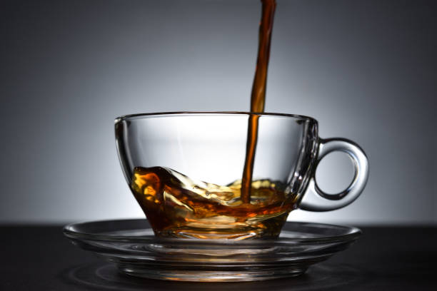 istock Pouring coffee on a transparent cup on black background 1221098788