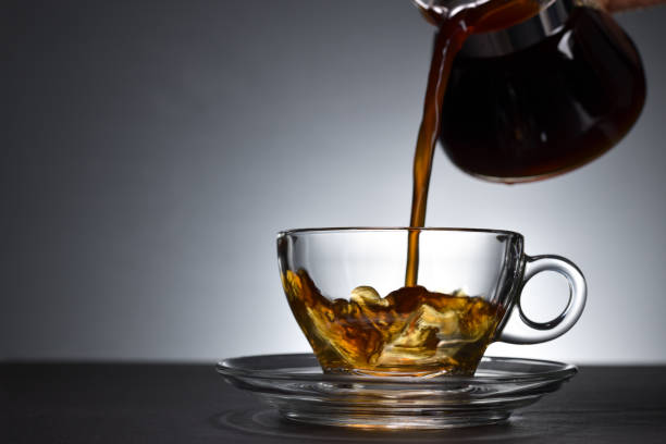 istock Pouring coffee on a transparent cup on black background 1221098790