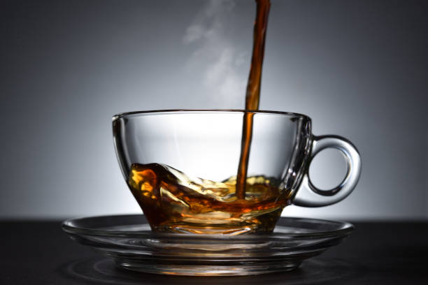 istock Pouring coffee with smoke on a transparent cup on black background 1221098799