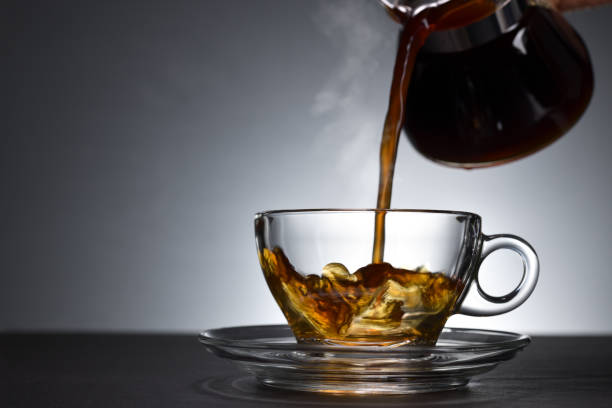 istock Pouring coffee with smoke on a transparent cup on black background 1221098815