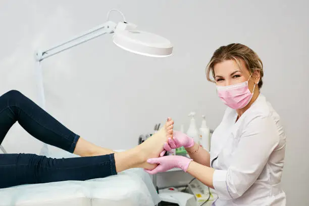 Photo of Portrait of a young woman doing the pedicure in a salon.