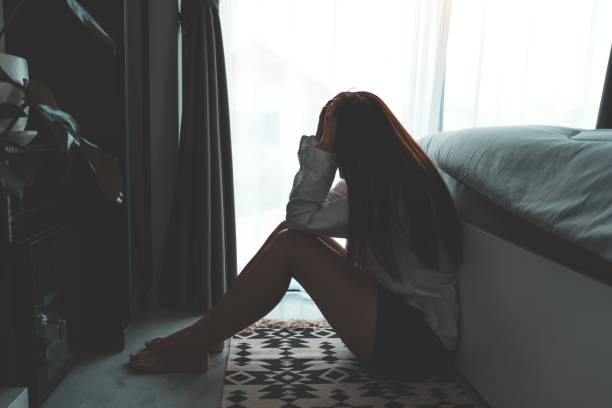 istock Depressed woman sitting head in hands in the bedroom with low light environment dramatic concept 1221101874