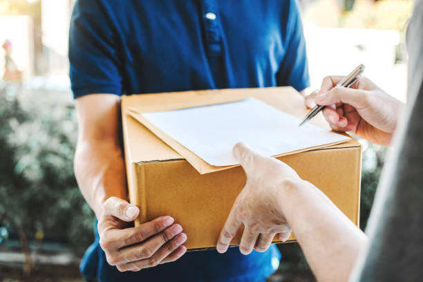 delivery concept asian man hand accepting a delivery boxes from professional deliveryman at home - postal worker truck driver delivering delivery person imagens e fotografias de stock