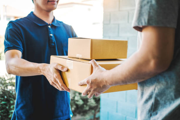 concepto de entrega asian man mano aceptando una entrega de cajas de reparto de repartidor profesional en casa - bulto fotografías e imágenes de stock