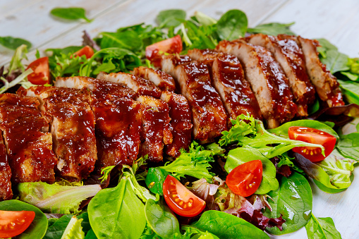 Baked spare baby back ribs with green salad and tomato.