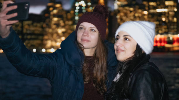 dwie dziewczyny cieszą się wspaniałą nocą w nowym jorku przed panoramą manhattanu - large transportation bridge famous place zdjęcia i obrazy z banku zdjęć