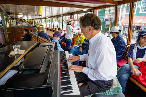 A senior are playing piano for tourists at old steamer Earnslaw, Main Town Pier, Lake Wakatipu, Otago, New Zealand.