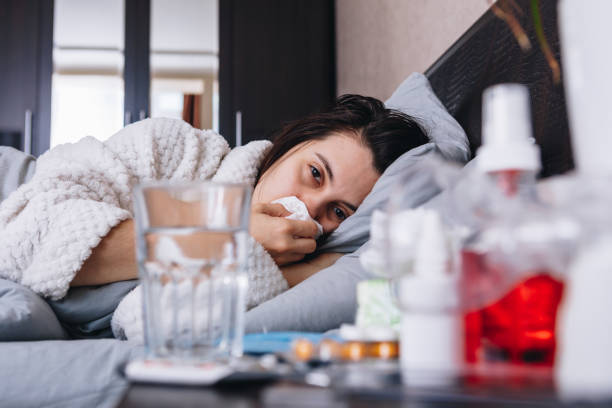 istock young sick woman in bed drinks pills 1221125184