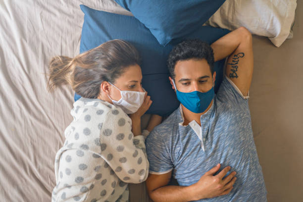 coppia a casa sdraiata a letto passando il tempo di quarantena - cold and flu flu virus bed couple foto e immagini stock
