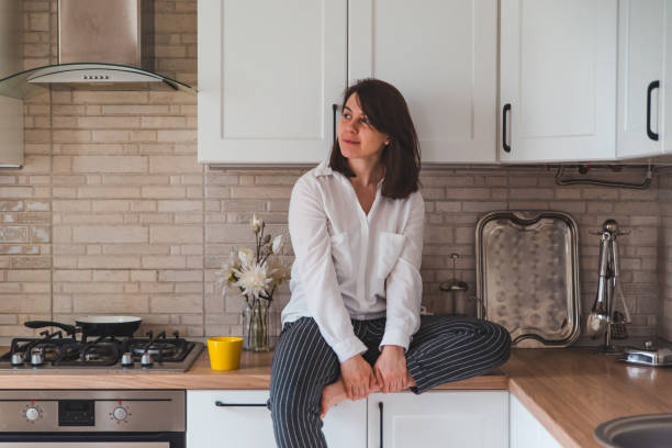 istock smiling pretty woman sitting on kitchen table with yellow tea mug 1221126551