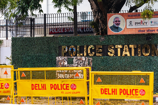 New Delhi, Delhi, India: Entrance of a police station with yellow barricades on the road in central part of the city. Golden text written outside a blocked Indian government office.