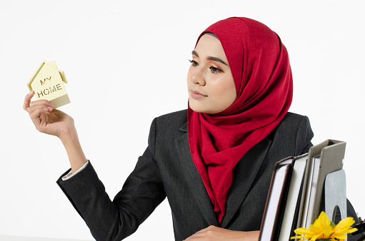 young woman with hijab savings money for her new home against white background