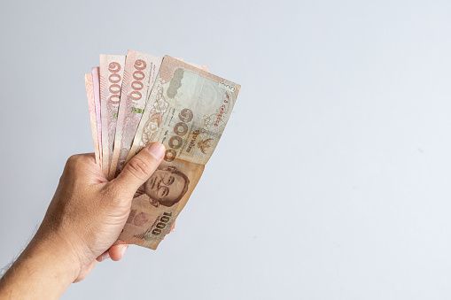 dinero tailandés en la mano sobre fondo de mesa blanco photo