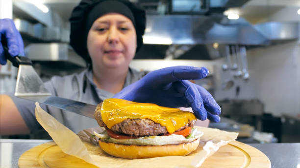 istock Female chef is preparing a delicious burger with cheese at restaurant kitchen 1221133557