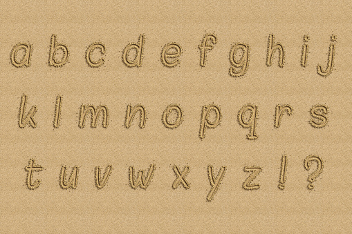 Alphabet written on the shore of a beach