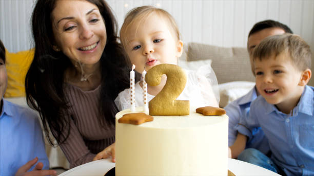 Cute little child girl is blowing the candles on birthday cake stock photo
