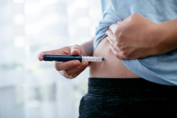 la mujer está haciendo una inyección de insulina en el estómago. foto de stock - insulin fotografías e imágenes de stock