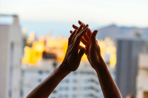 Close-up of group of business people clapping hands together while standing against the white background