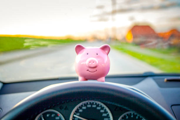 piggy bank sitting on the dashboard during driving a car - fuel efficiency imagens e fotografias de stock