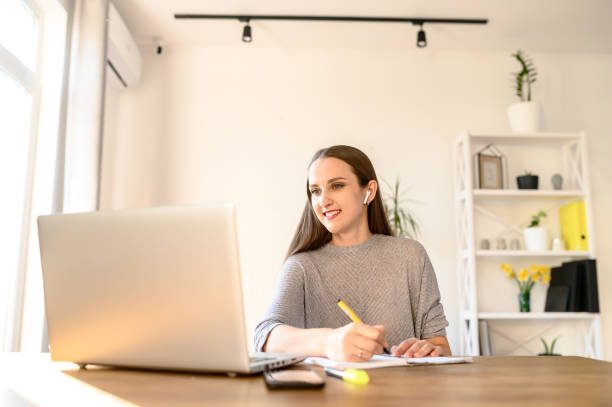 istock A young woman sits at a table with a laptop 1221146329