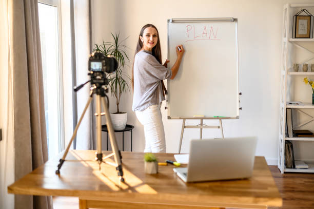 istock Young woman with flipchart records video lessons 1221146348