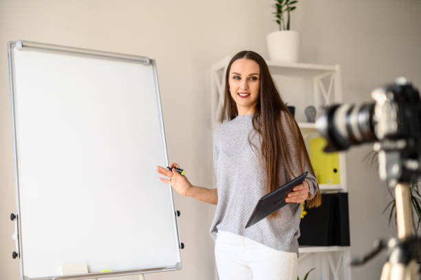istock Young woman with flipchart records video lessons 1221146405