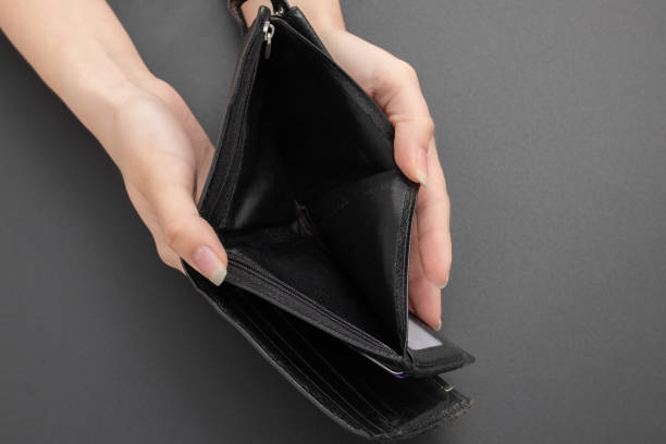 istock Empty wallet without money in female hands on a black background 1221150031