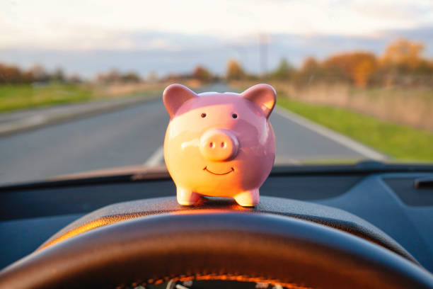 piggy bank sitting on the dashboard during driving a car - fuel efficiency imagens e fotografias de stock