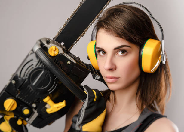 istock Girl in overalls with a chainsaw in white background 1221150356