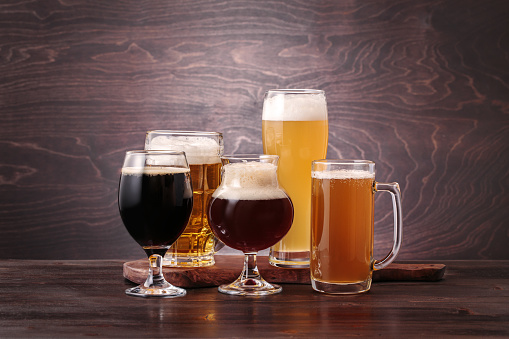 Mugs with different sorts of beer on a wooden table. Beer tasting concept