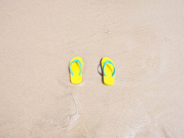 istock yellow sandal on beige sand 1221153107